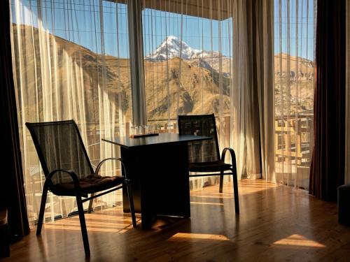a table and chairs in a room with a view of a mountain at Vache Hotel in Kazbegi