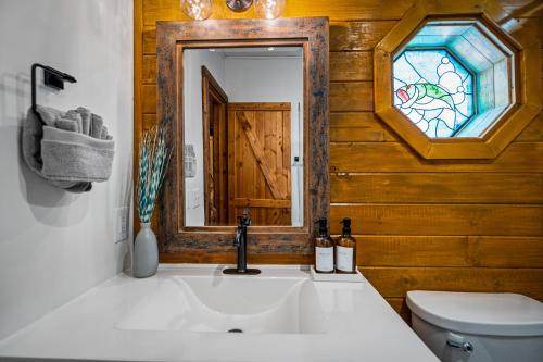 a bathroom with a sink and a toilet and a mirror at Freedom Creek Hideaway-Veteran Host-Pet Friendly-Single nights-Newly Renovated!! in Pigeon Forge