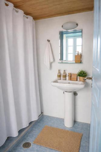 a white bathroom with a sink and a mirror at Maestro apartment Chalki in Halki