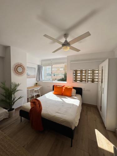 a bedroom with a bed with orange pillows and a ceiling fan at Ideal parejas Estudio Granadella en Jávea in Platja de l'Arenal