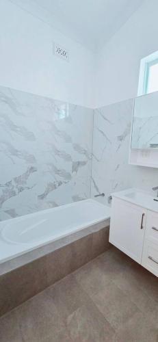 a bathroom with a shower and a tub and a sink at Full house - Heritage Charm Meets Modern Ease in Midland Junction