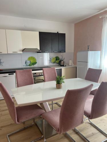 eine Küche mit einem weißen Tisch und rosa Stühlen in der Unterkunft Nedi's Nest - Cozy Countryside Retreat Under Palmtrees in Dutovlje
