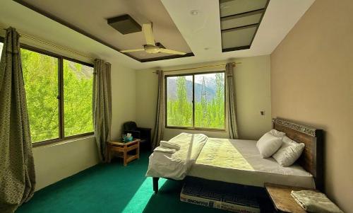 a bedroom with a bed and two windows at Flora Inn Skardu in Skardu