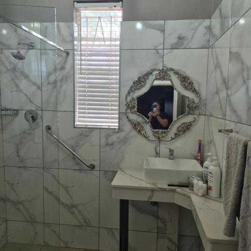 a bathroom with a sink and a mirror at Kleingeluk Guest Cottages in Louis Trichardt