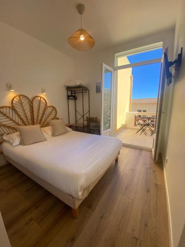 a bedroom with a large bed and a balcony at Hôtel L'Oustaou in Le Lavandou