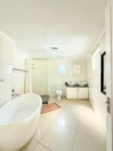 a white bathroom with a tub and a toilet at The Stillhouse Guest House in Edenvale