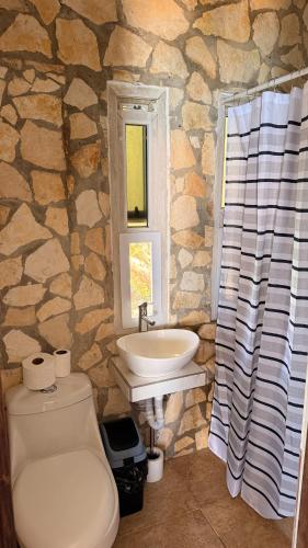a stone bathroom with a toilet and a sink at Del Mar Beach House in Nimá