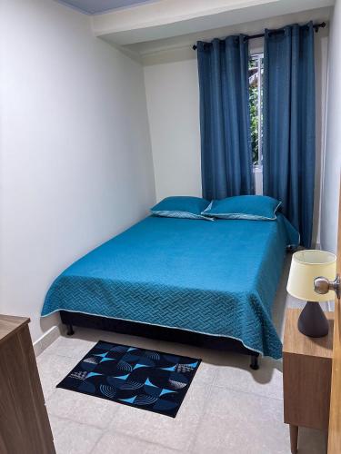 a bedroom with a bed with blue sheets and a window at Apartamento elegante en el Centro in Cocorná