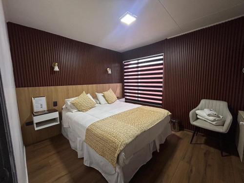 ein Schlafzimmer mit einem großen Bett und einem Stuhl in der Unterkunft Hotel Milodon in Puerto Natales