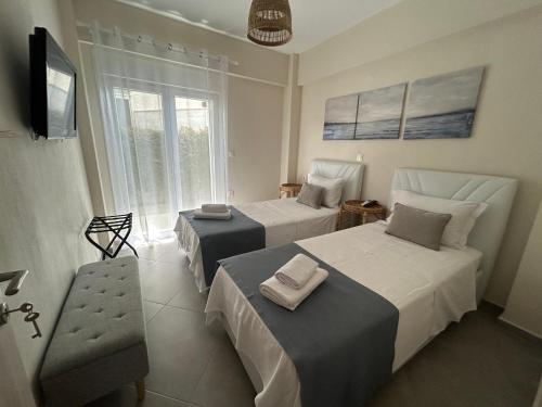 a bedroom with two beds and a tv and a window at Coral Nikiti Apartments I in Nikiti