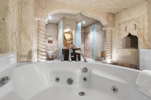a white bath tub in a room with a fireplace at Tatlı Kaya Cave Otel in Ürgüp