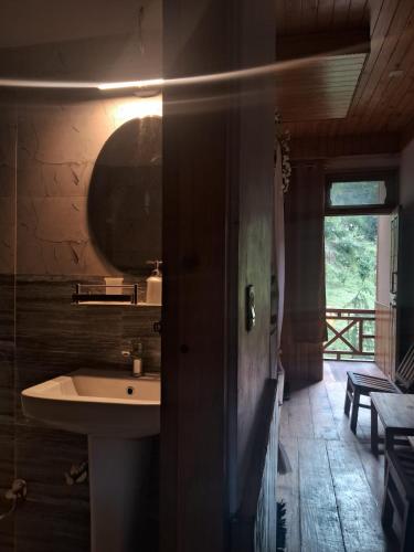 a bathroom with a sink and a mirror and a window at Bhindeshi Tara Stays Jibhi Mihar in Jibhi