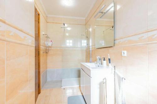 a bathroom with a sink and a shower and a mirror at The Refuge Mosteiros house in Mosteiros