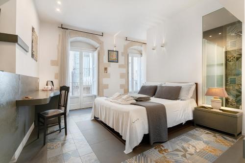 a bedroom with a bed with a desk and a chair at Iblainsuite in Ragusa