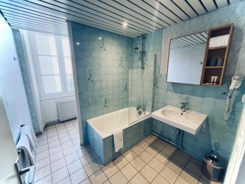 a bathroom with a tub and a sink and a mirror at Hôtel des Cymaises in Semur-en-Auxois