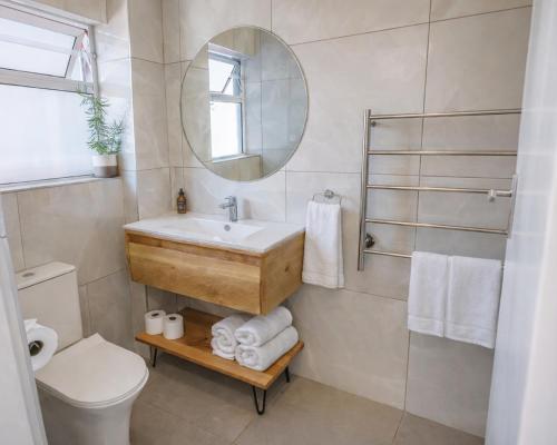 a bathroom with a sink and a toilet and a mirror at Modern Seaside Apartment in Fish Hoek
