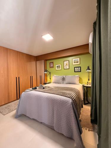 a bedroom with a bed and a green wall at Apartamento 1 quarto Goiânia in Goiânia
