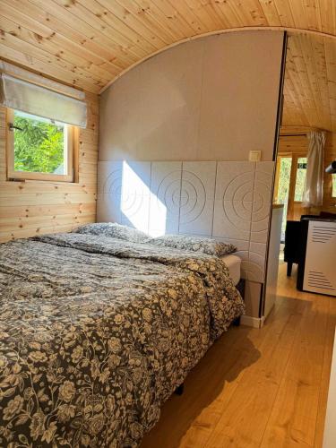 a bedroom with a bed in a wooden room at Pipowagen aan het Wandelpad in Lanaken