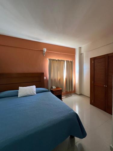 ein Schlafzimmer mit einem blauen Bett und einem Fenster in der Unterkunft Hotel Sol del Pacifico in Lázaro Cárdenas