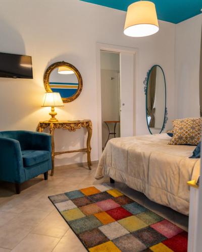 a bedroom with a bed and a chair and a mirror at Le Caserie Locanda di Charme in Marsala