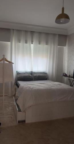 a bedroom with a large white bed with curtains at Charme appartement in Mohammedia