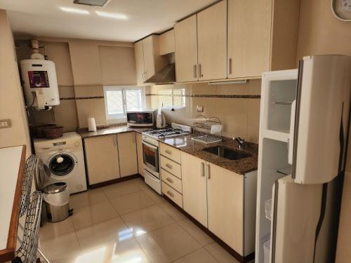 a small kitchen with white cabinets and a refrigerator at Piero House in Villa Mercedes