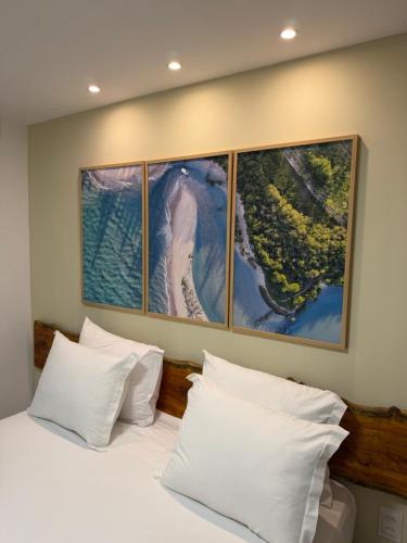 a bedroom with a bed with four paintings on the wall at Maré Suítes Maragogi in Maragogi