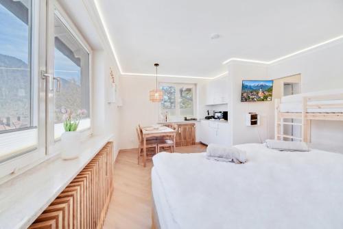two beds in a white room with a kitchen at Zuhause am Kurgarten in Bad Reichenhall
