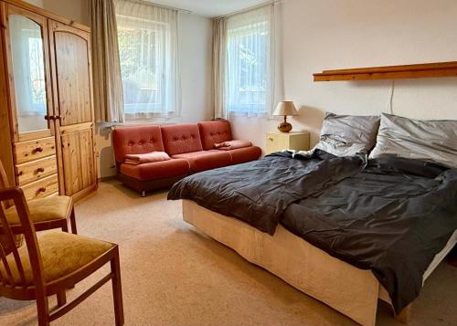 a bedroom with a bed and a chair and a couch at Gemütliche Ferienwohnung mit Sauna & Terrasse in Monzingen