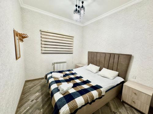 a bedroom with a bed with a checkered blanket at Three Home in Quba
