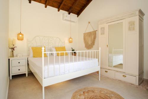 a white bedroom with a crib and a mirror at Petit Palace in Lefkimmi