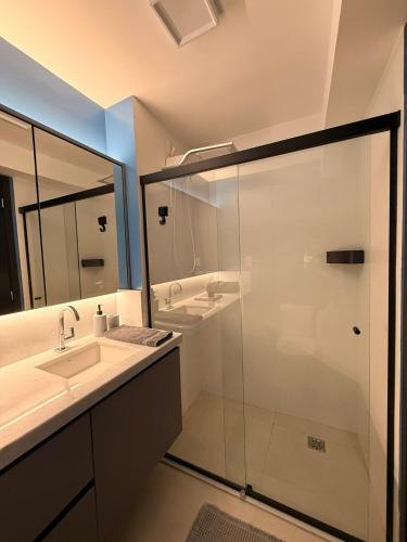 a bathroom with a glass shower and a sink at Apartamento 1 quarto Goiânia in Goiânia