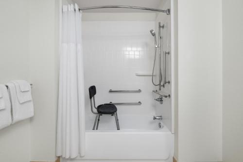 a black chair sitting in a shower in a bathroom at Garner Hotel Madison - Huntsville Airport by IHG in Madison