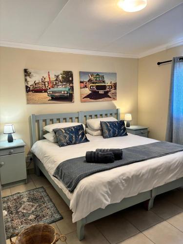 a bedroom with a large bed with two pictures on the wall at Gamtoosberg Cottage in Oudtshoorn
