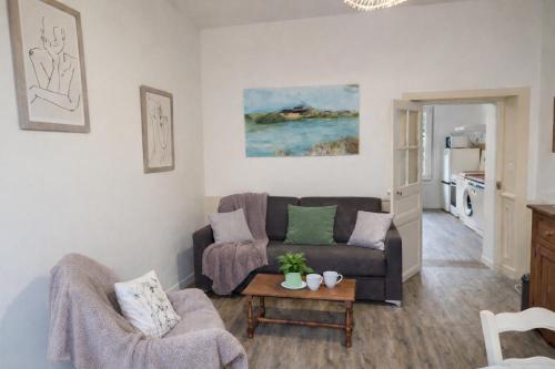 a living room with a couch and a table at Gîte Le Repos de Merlin - Paimpont, Forêt de Brocéliande in Paimpont