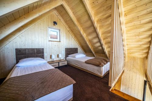 two beds in a attic room with wooden walls at Fajne Domki in Jastarnia