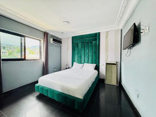 a bedroom with a bed with a green headboard at La Castrol Hotel Apartments in Limbe