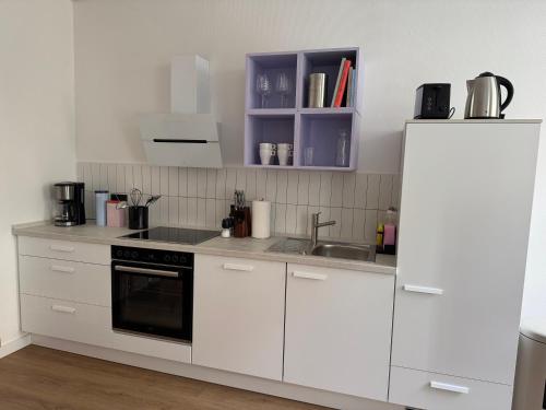 a kitchen with white cabinets and a sink and a refrigerator at Zum Alten Pasewalker Kaufmann Beletage in Pasewalk
