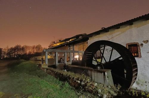 a train traveling past a building with a watermill at Il Vecchio Mulino Di Bairo in Bairo