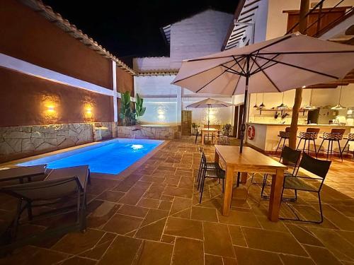 a swimming pool with a table and an umbrella at Casa Mónica Barichara in Barichara