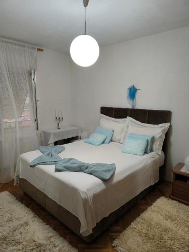 a bedroom with a large white bed with blue pillows at Apartmani Mislav in Slatine