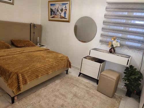 a bedroom with a bed and a desk and a mirror at Maison du Bonheur in Ariana