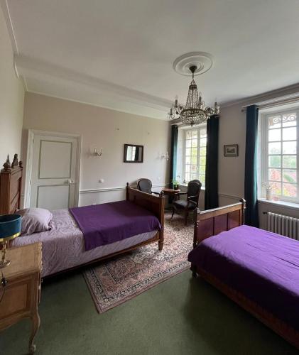 a bedroom with two beds and a table and a chair at Charmante maison en pleine campagne in Rollancourt
