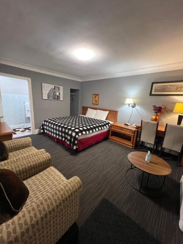a hotel room with a bed and a couch and a table at Tulip Motel in Woodstock