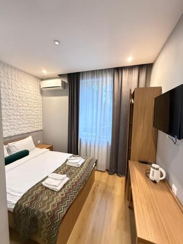 a hotel room with a bed and a flat screen tv at Downtown Hotel in Tbilisi City