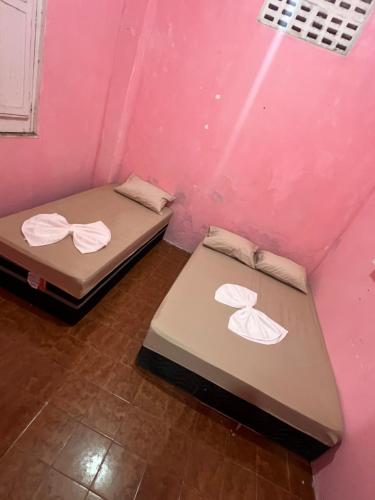 two beds in a room with pink walls at Pousada Oliveira in Cachoeira