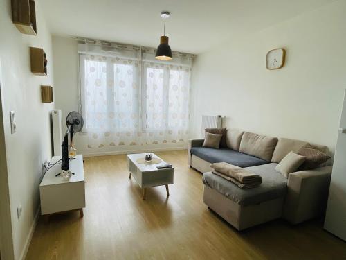 a living room with a couch and a table at Appartement cosy proche Paris CDG RER B Disneyland Paris Parc Astérix in Le Blanc-Mesnil