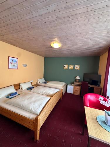 a room with two beds and a table and a chair at Eiscafé - Pizzeria Antonio in Lichtenau