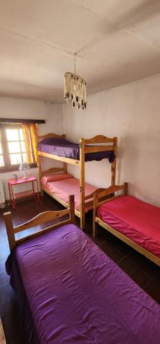 a room with three bunk beds and a chandelier at Gran Casa Hostel&Camping in Tilcara