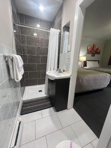 a bathroom with a shower and a sink and a bed at Tulip Motel in Woodstock